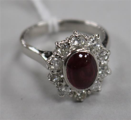 An 18ct white gold, cabochon garnet and diamond oval cluster ring, size M.